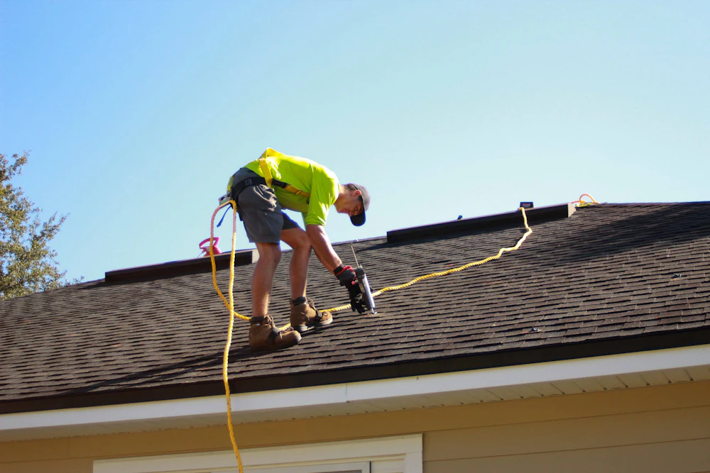 Roofer repairing a roof with a power drill