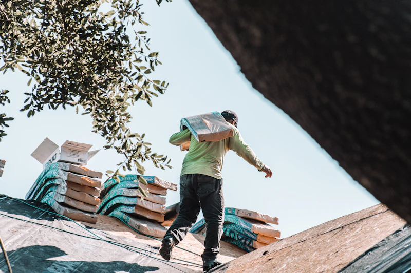 Roofer carrying shingles across a residential roof